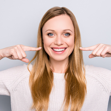 woman smiling and pointing to teeth 