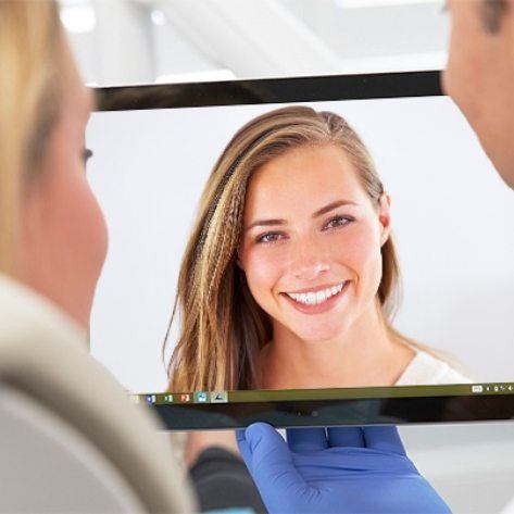 Dentist and patient looking at virtual smile design on computer screen