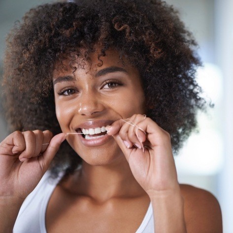 Woman flossing teeth to prevent dental emergencies