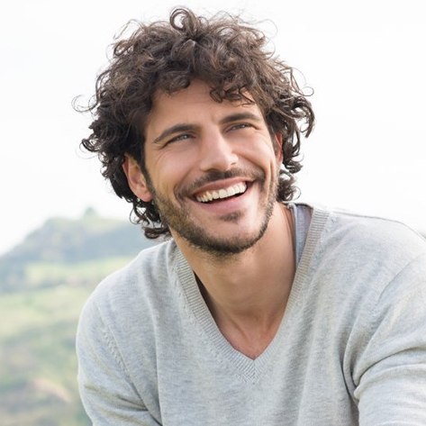 a man smiling after receiving a tooth colored filling