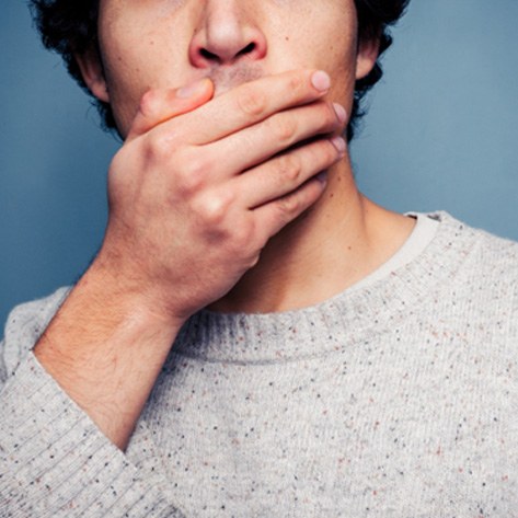 An upset man covering his mouth