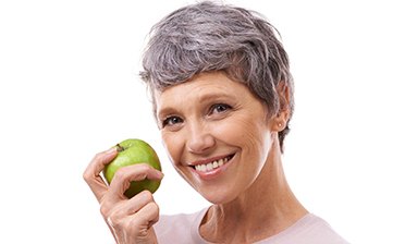 smiling woman holding a green apple