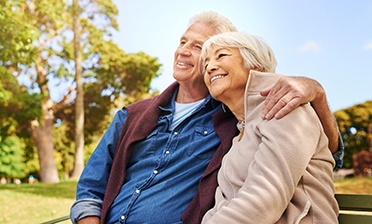 senior couple sitting on a park bench 