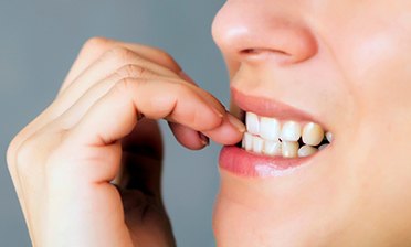 A closeup of a woman biting her nails 