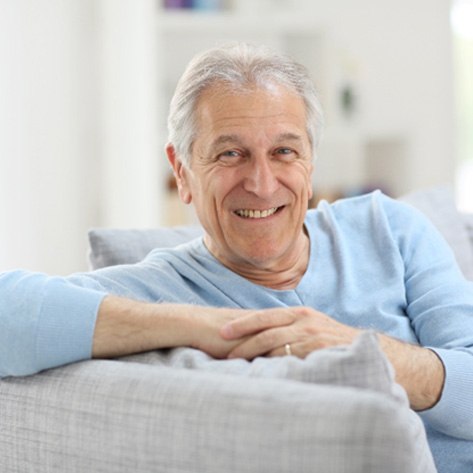 Senior man leaning on couch and smiling