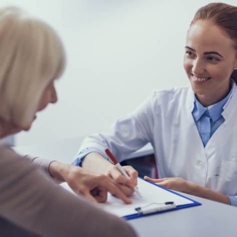 Dental team member explaining the cost of dental implants to patient