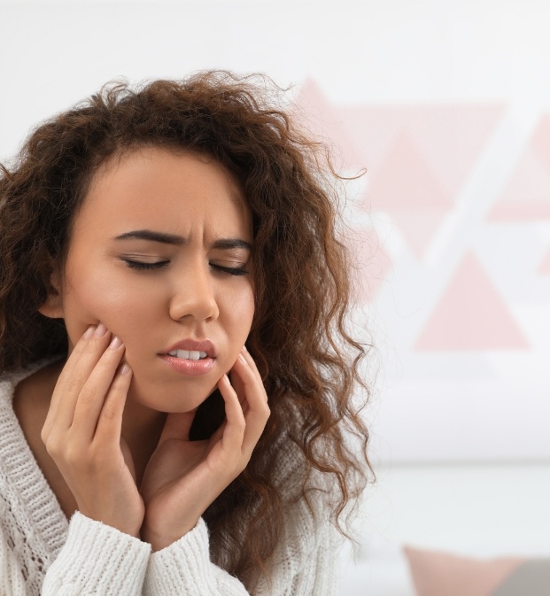 Woman holding both sides of her face in pain