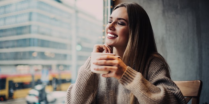 Smiling woman sitting at table in coffee shop by a window