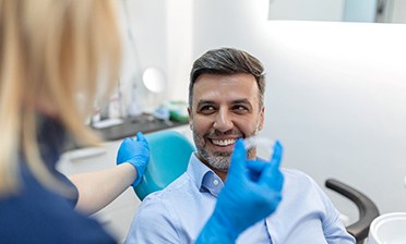 Patient smiling at dental assistant holding Invisalign aligner