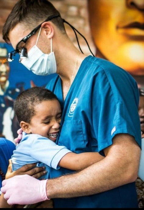 Doctor Cecchini hugging young dental patient