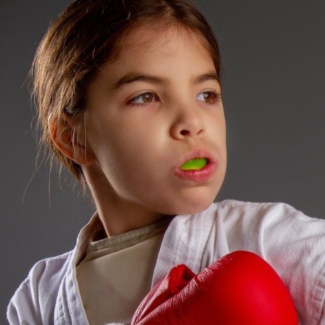 Young girl with boxing gloves wearing athletic mouthguard