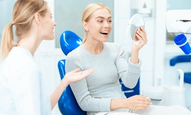 a patient smiling and checking her new veneers 