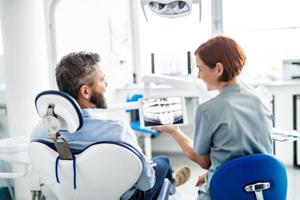 Dentist smiling at patient while reviewing his X-ray