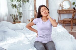 Woman with aches and pains sitting up in bed
