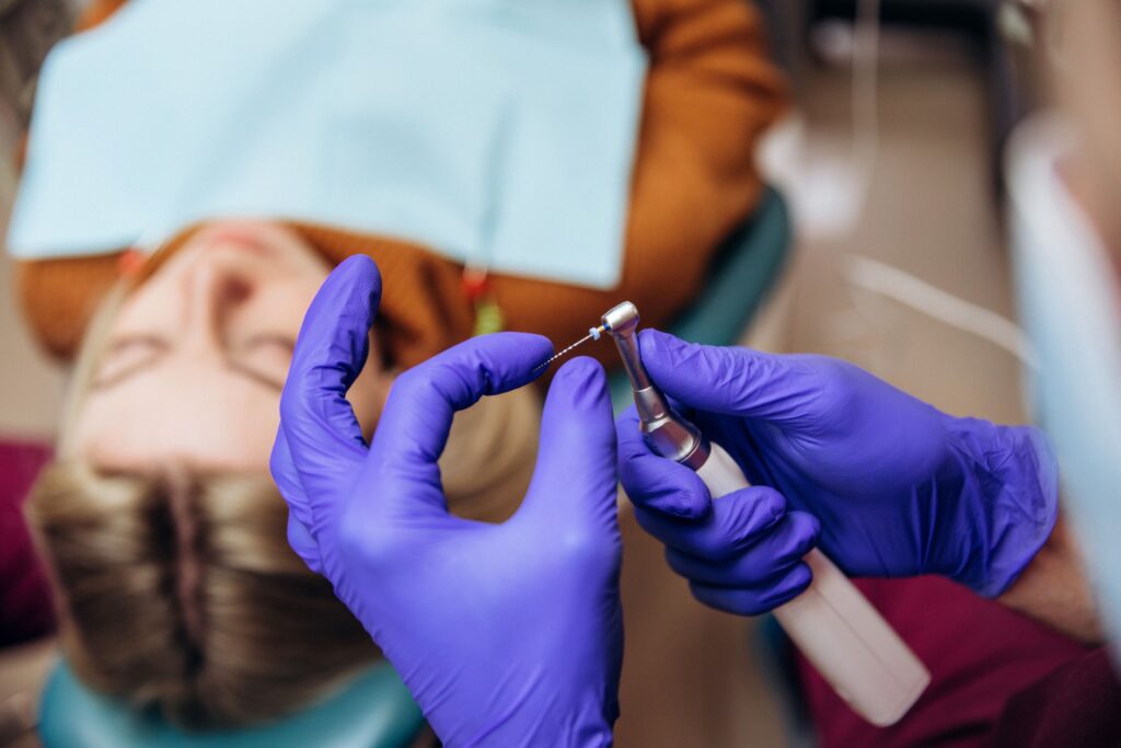 Dentist in blue gloves preparing dental instrument for root canal