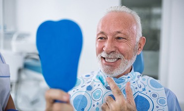 senior man pointing to his new smile with dental implants in Chicago 
