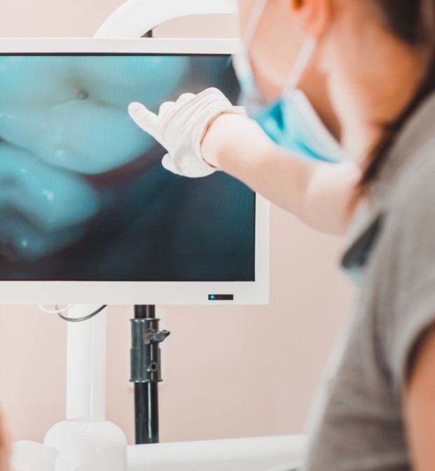 Dentist pointing to close up images of teeth on computer screen